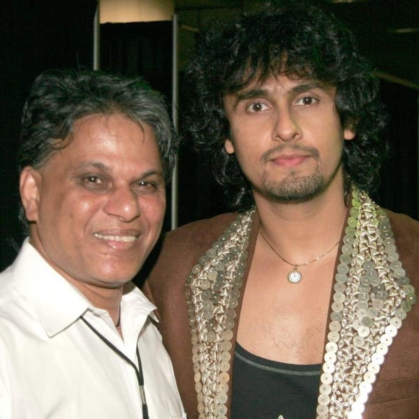 Two men, one older with a white shirt and one younger with curly hair and a sequined jacket.
