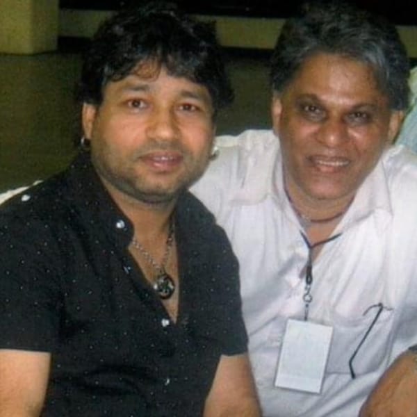 Two men, one in a black shirt and the other in a white shirt, smiling at the camera.