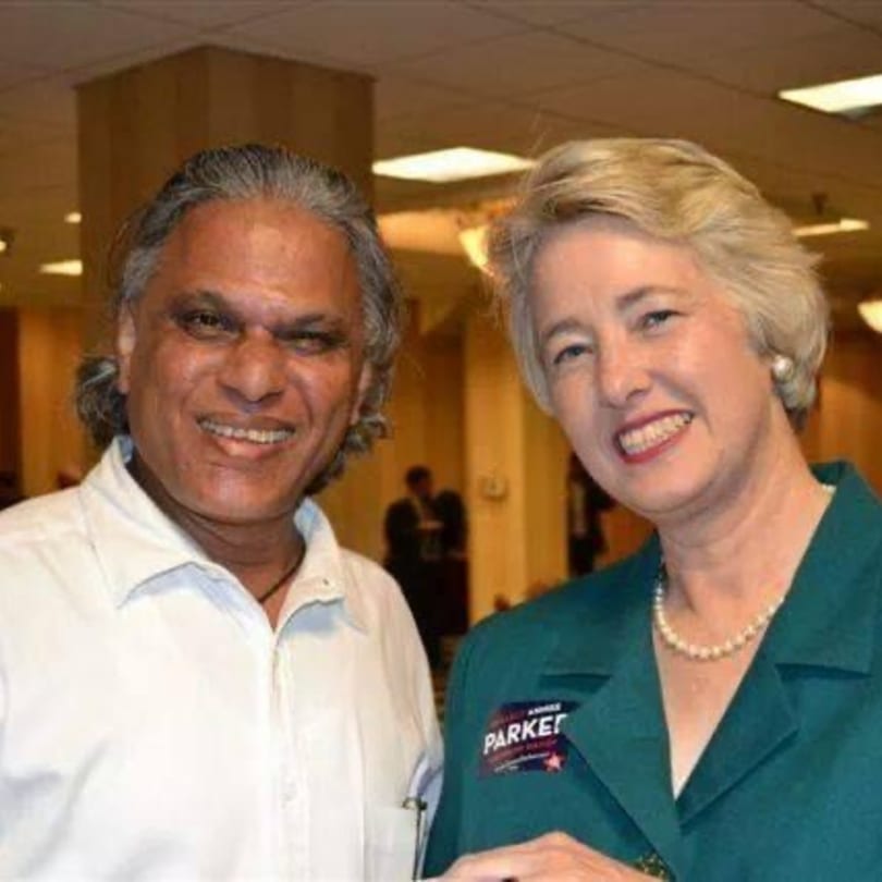 A man with long gray hair and a woman in a green jacket smiling at the camera.