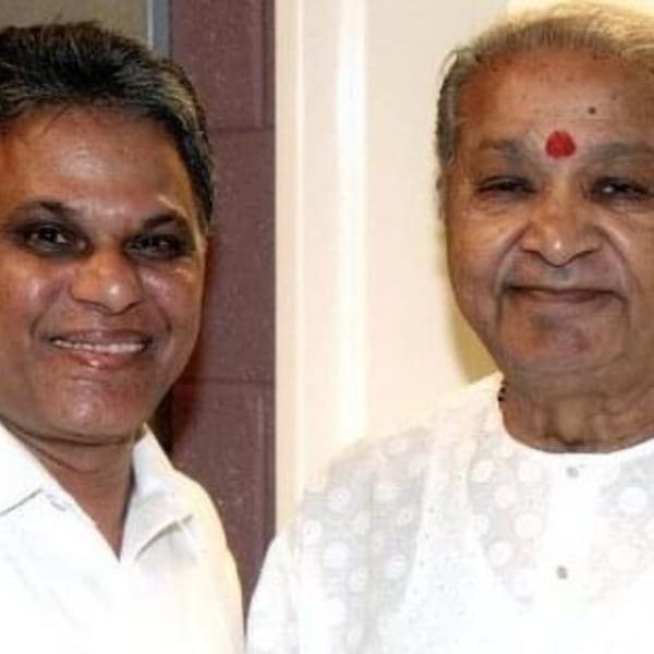 Two men, one younger and one older with a red bindi, smiling at the camera.