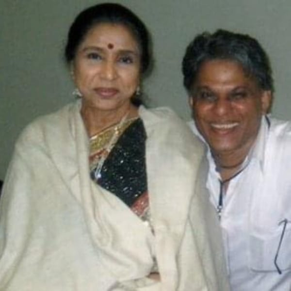 Asha Bhosle and R.D. Burman smiling together, with Bhosle wearing a shawl over a sari.