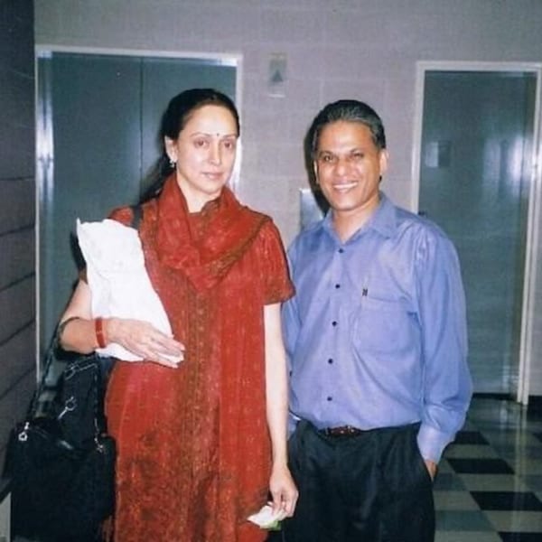 A woman in a red dress and a man in a blue shirt smiling at the camera.